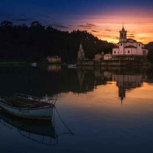 Imagen del espectacular atardecer en la ría de Niembro con la iglesia y el cementerio al fondo