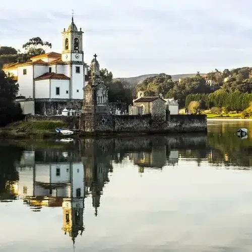 Imagen de la Iglesia de Nuestra Señora de los Dolores reflejada en la ría de barro durante la marea alta