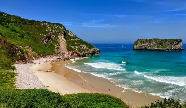Imagen de la playa de Andrín con el Castro de Ballota detrás.