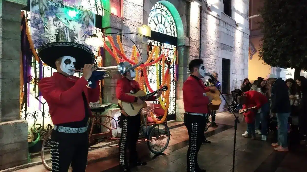 Mariachis con la cara pintada de calavera actúan ante el pórtico decorado por el Samaín en Llanes