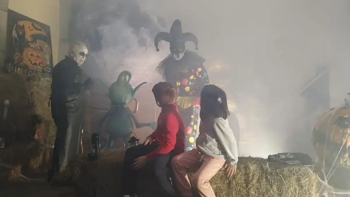 Dos niños sentados en balas de paja contemplan la decoración de Halloween en Llanes