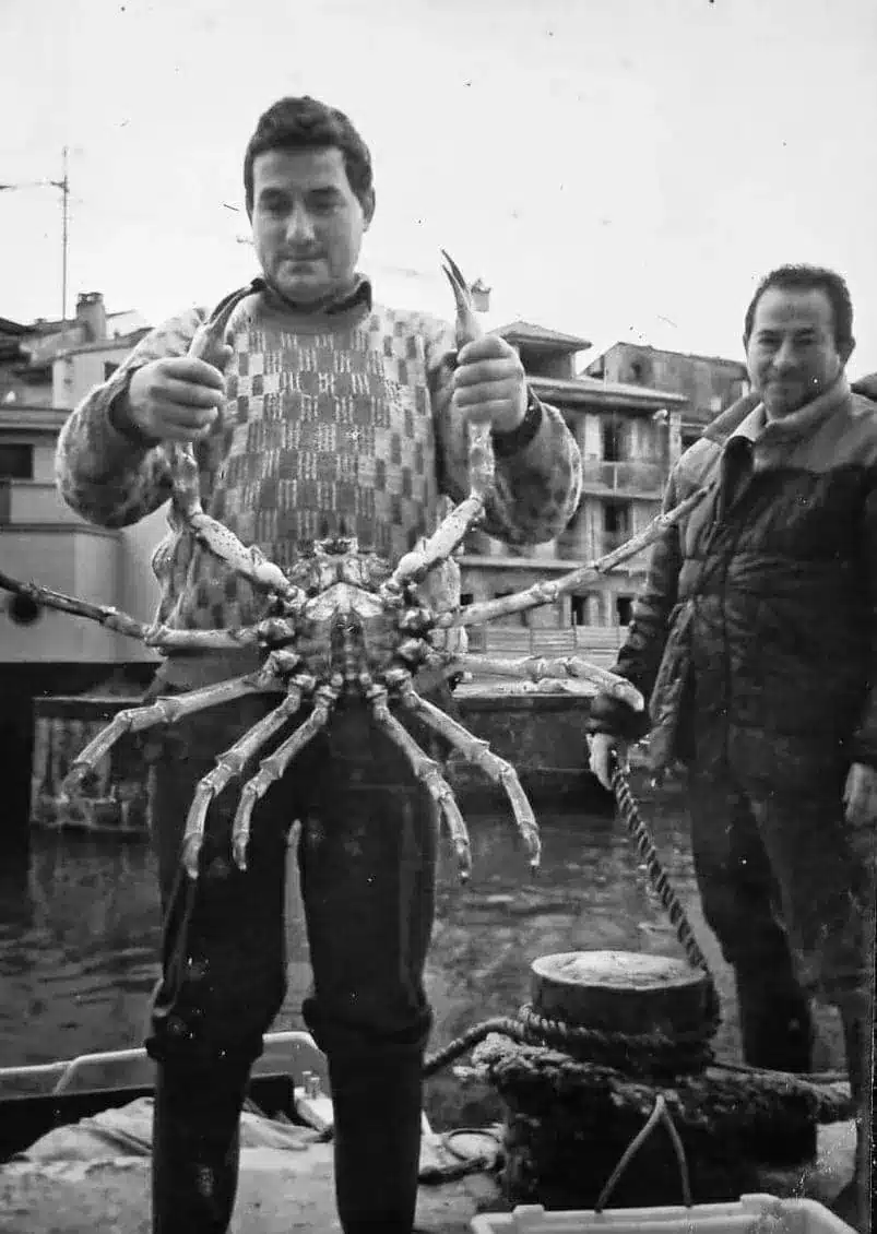 Pescadores de Llanes con una centolla en el puerto, fotografía antigua del Llanes marinero